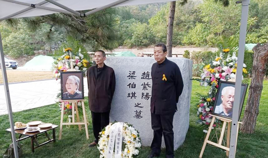 10月18日,赵紫阳夫妇墓碑前摆放着出席骨灰安葬仪式的亲友们献的鲜花。赵紫阳之子赵二军(右)立于碑前。(美国之音)
