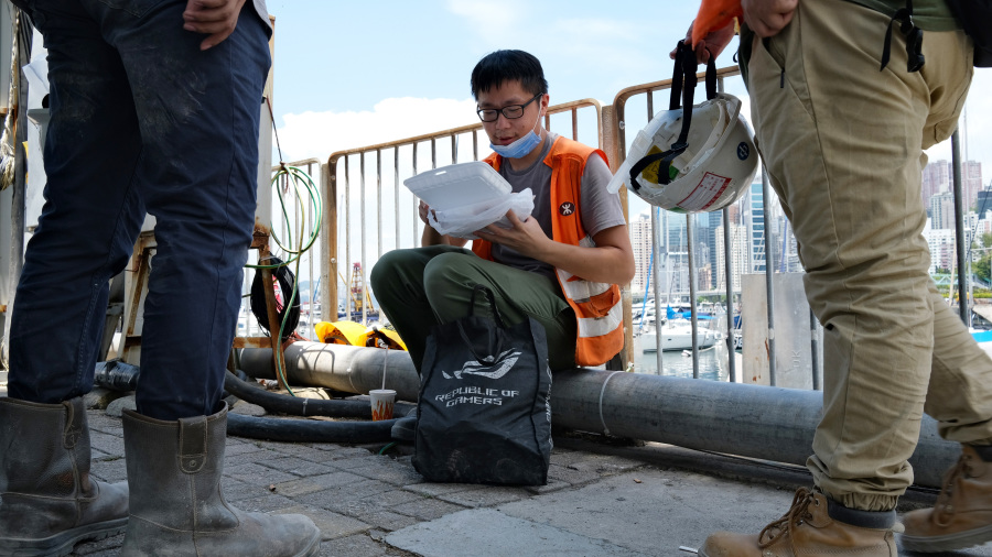 香港影帝周润发心痛市民户外工作时,还必须当街吃饭,宛如乞丐“遍地开餐”。图为7月29日,港府颁布禁止在餐厅堂食的防疫措施生效首日,香港上班族和工人被迫烈日下在街头吃午饭。(图片来源:ANTHONY WALLACE/AFP via Getty Images )