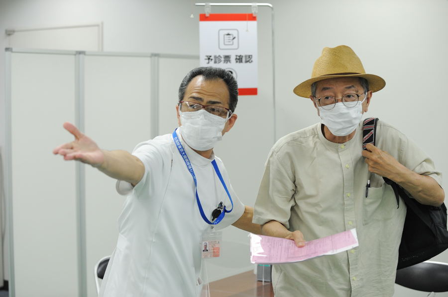 6月9日,日本东京,一名工作人员正指引一名老者去接种疫苗。(示意图/非本文人物/图片来源:David Mareuil - Pool/Getty Images)