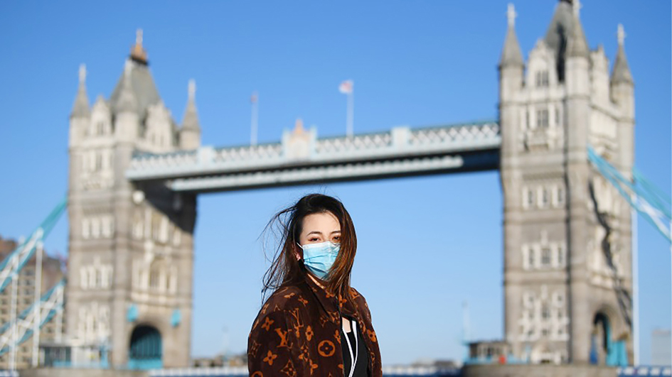 一名戴口罩的女士在英国伦敦塔桥前合影留念。(Alex Davidson/Getty Images)