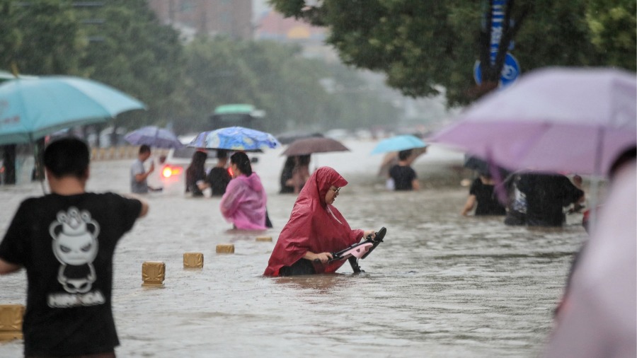 2021年7月20日,中国河南省郑州市人们在暴雨中涉水走过街道。(图片来源:Getty Images)
