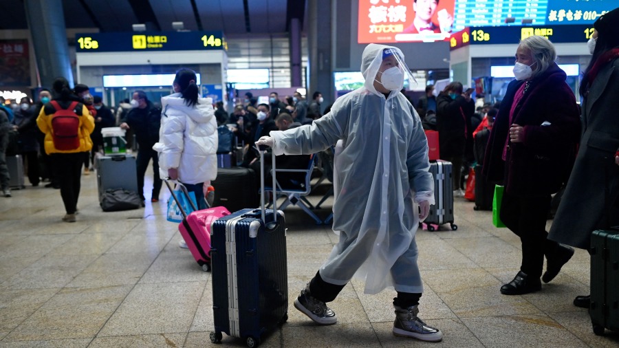 2023年1月12日,一名穿着雨衣的孩子在北京火车站拉着行李。(图片来源:WANG ZHAO/AFP via Getty Images)